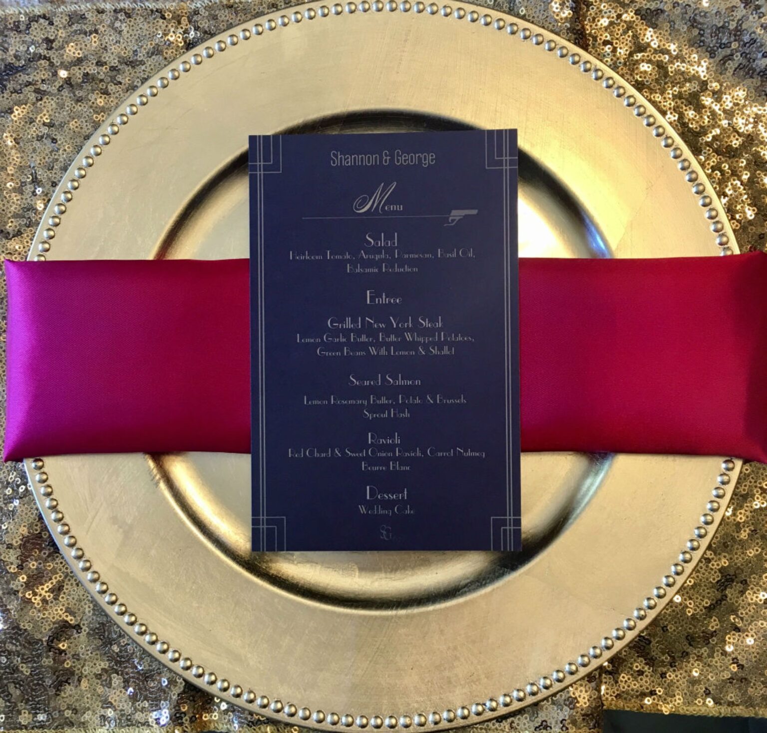 A navy menu card on a fuchsia napkin and a gold sequin charger