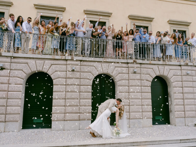 Guests throw petals from the balcony as the couple kiss below. Brooke and Austin's wedding at Villa Cipressi, Lake Como, Detito Photography