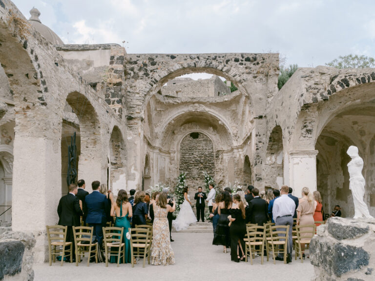 Guests gathered for the ceremony among roofless stone ruins. Erica and Dustin's wedding at the Aragonese Castle, Ischia, Detito Photography