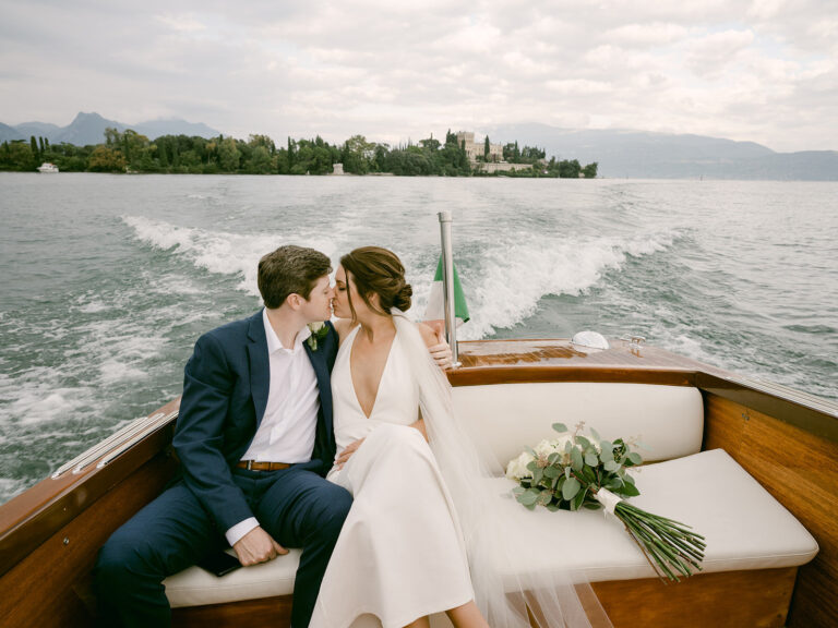 The couple on a wooden boat leaving the island. Sam and Lance's elopement on Garda Island, Lake Garda, Detito Photography