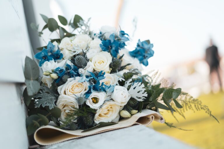 A bouquet of white roses, blue delphinium and thistle laid on a ceremony bench, Diamante Your Wedding in Italy