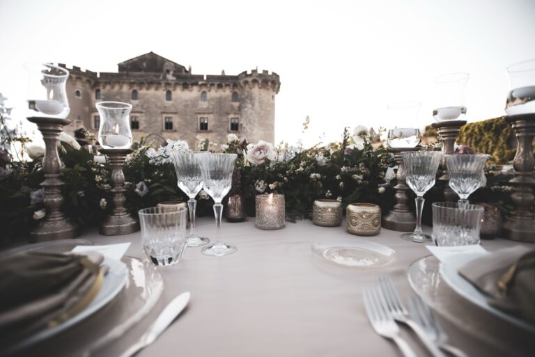 Table detail at the Castle of Palo: cut-crystal glasses, candle holders and a low garland of roses and greenery, Diamante Your Wedding in Italy