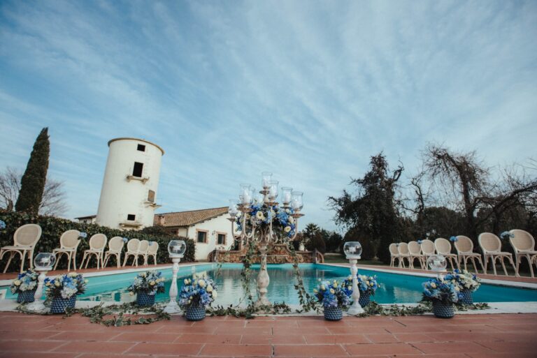 Blue and white flowers and a tall candelabra arranged around the pool at Tenuta di Fiorano on the Appia Antica, Diamante Your Wedding in Italy