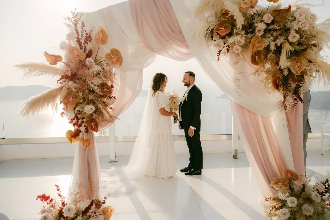 A pastel floral arch for a ceremony above the caldera at Andromeda Villas, Santorini, Diamond Rock Santorini
