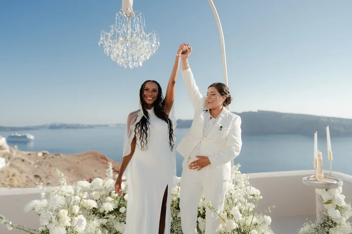 A couple celebrating among white flowers at Love Cave Venue, Santorini, Diamond Rock Santorini