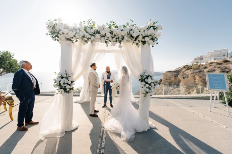 Vows beneath a white floral arch at Thermes, Santorini, Diamond Rock Santorini