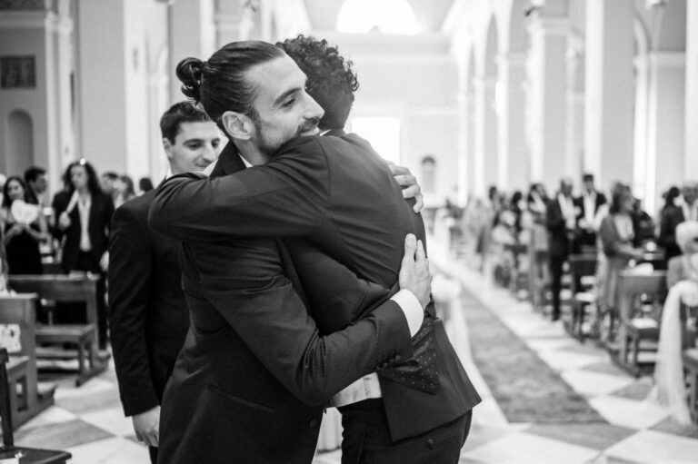 Two groomsmen embracing inside a church, in black and white, Diego Giusti Photographer