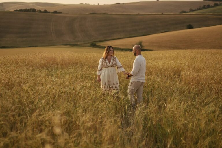A couple in a golden wheat field at sunset, the Tuscan hills behind, Diego Giusti Photographer