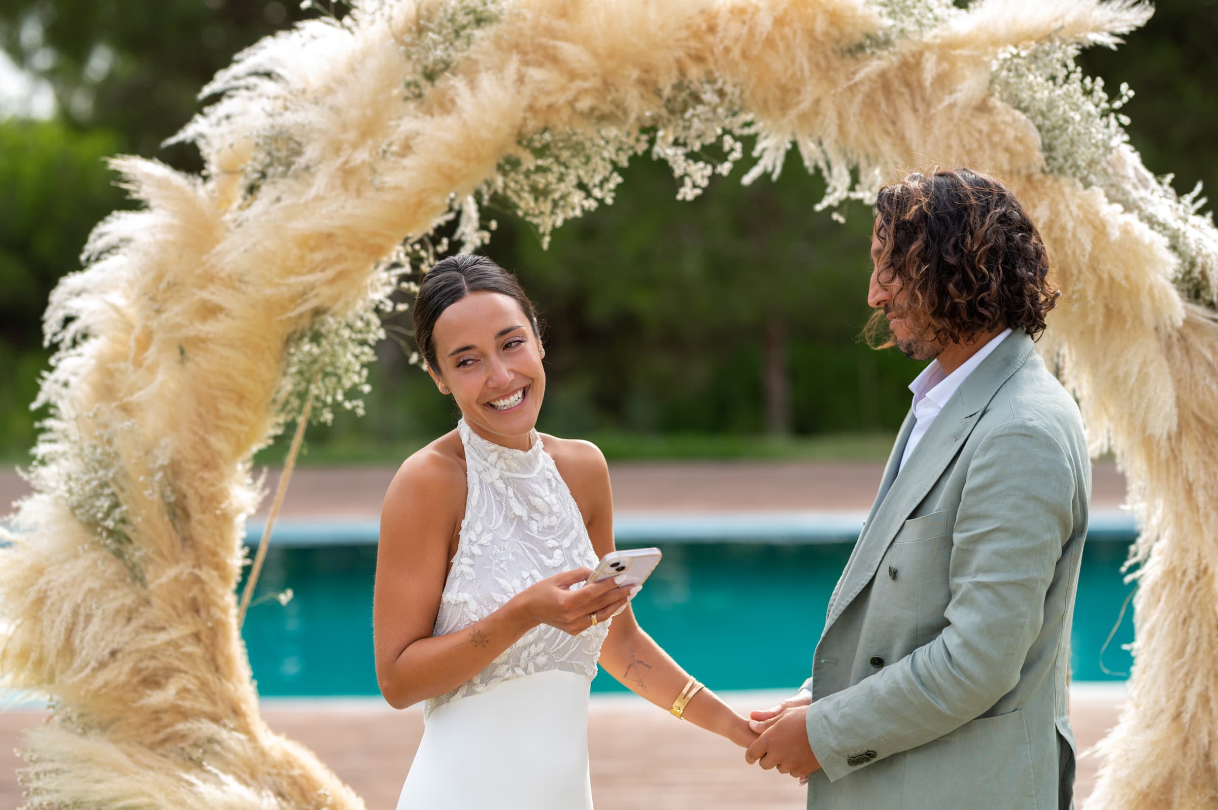 The couple hold hands beneath the pampas arch during their vows, Casal do Frade, Sesimbra, Dimas Frolov Photography