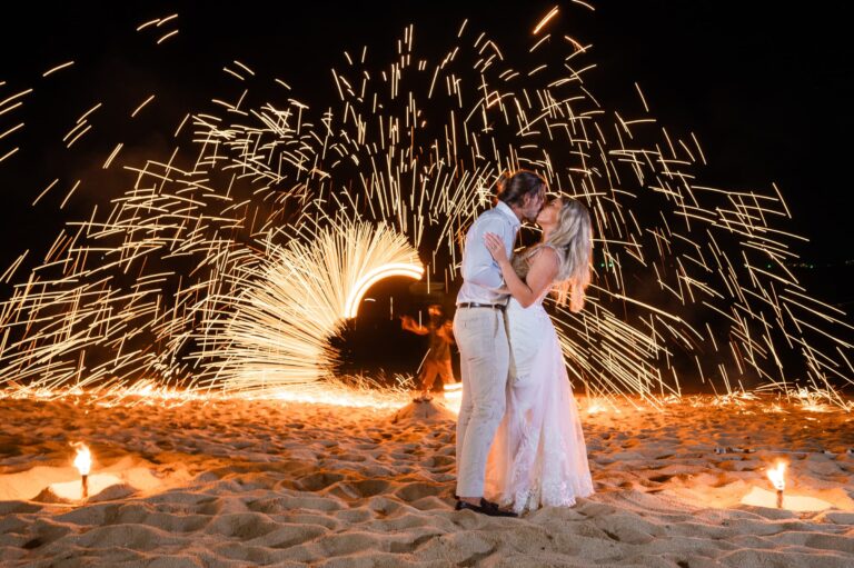 A kiss in front of a fire performer's spinning sparks on the beach at night, Dimas Frolov Photography