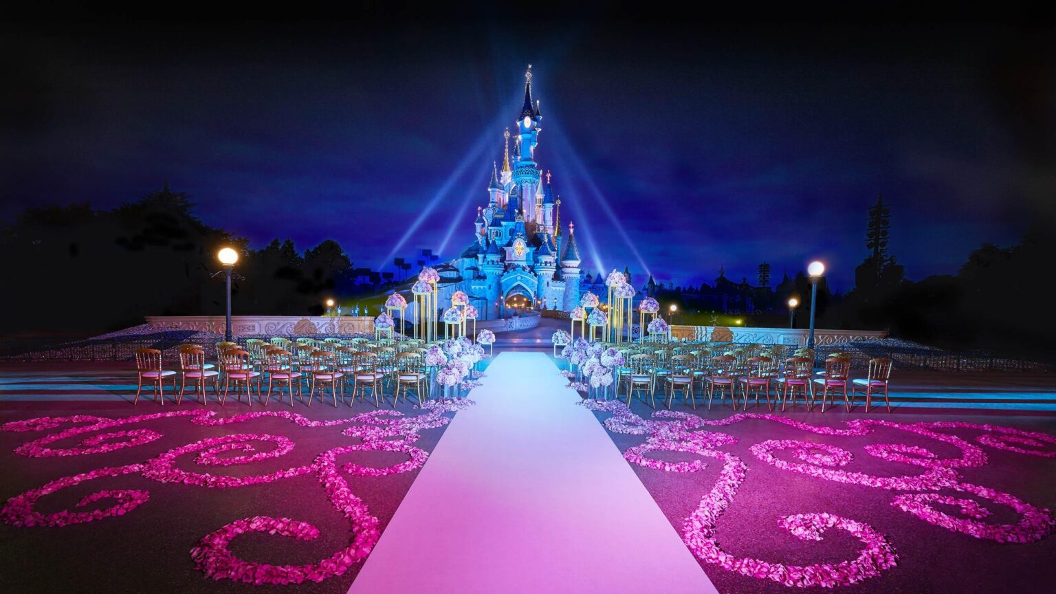 A wedding ceremony set before Sleeping Beauty Castle at night