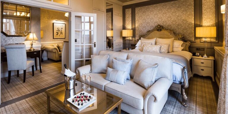 A bedroom with a sofa and a view across the room, Down Hall Country House Hotel