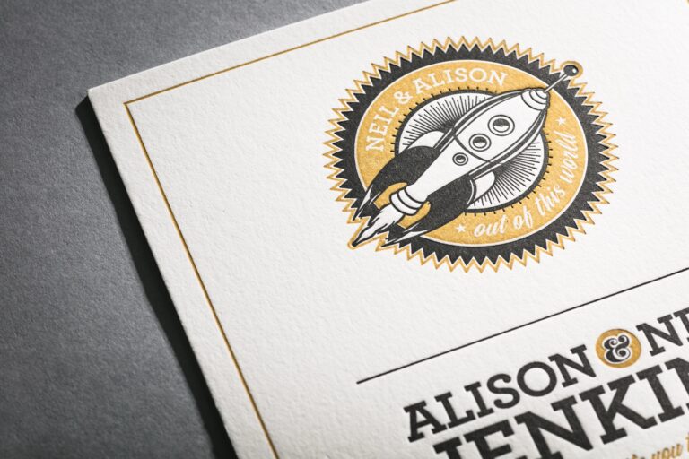 Letterpress invitation with a rocket badge illustration in black and gold, Downey Luxury Stationery