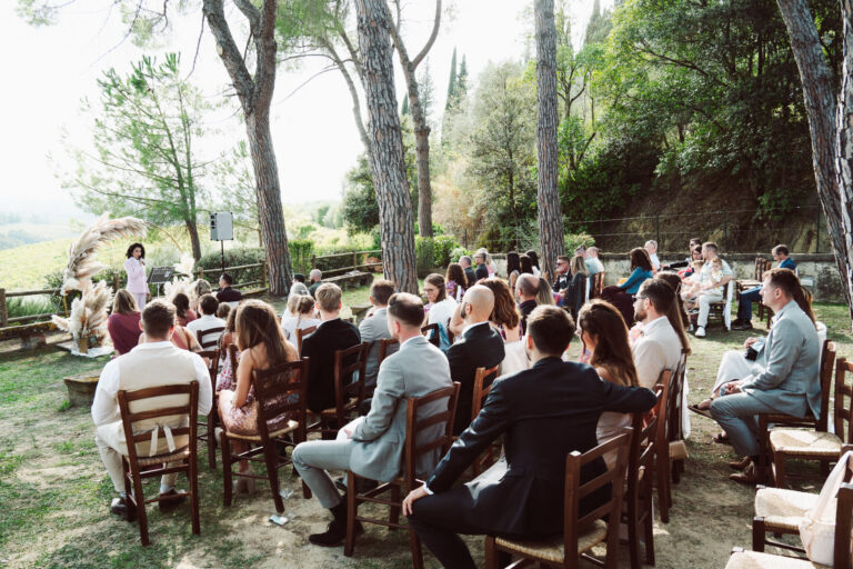 Guests seated on wooden chairs under pine trees for an outdoor Tuscan ceremony, Dr Tiziana Di Molfetta