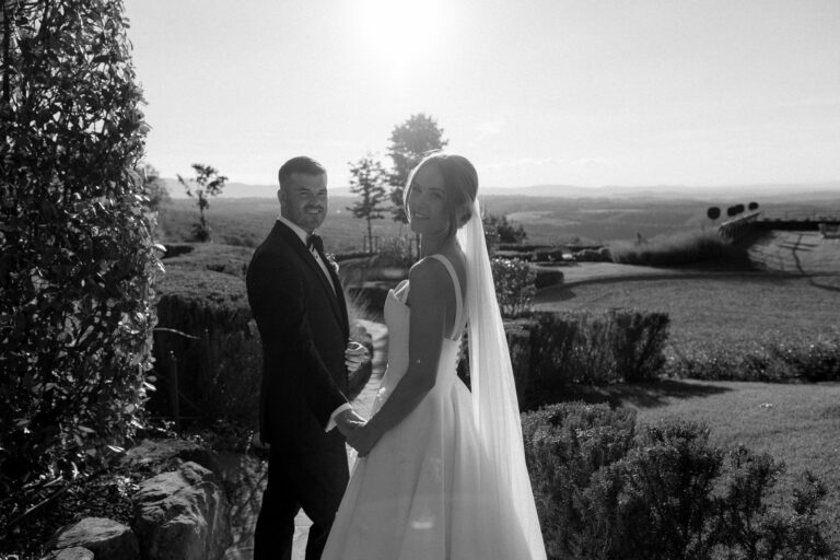 Black and white: the couple on a garden terrace above open fields, the sun behind them, Dream On Wedding Team