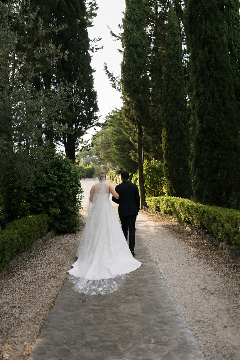 The couple walking up a gravel path between cypresses and clipped box hedges, Dream On Wedding Team