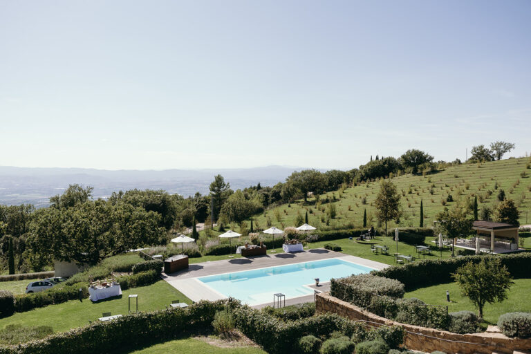 A pool and parasols on a terraced hillside, a wide plain beyond, Dream On Wedding Team