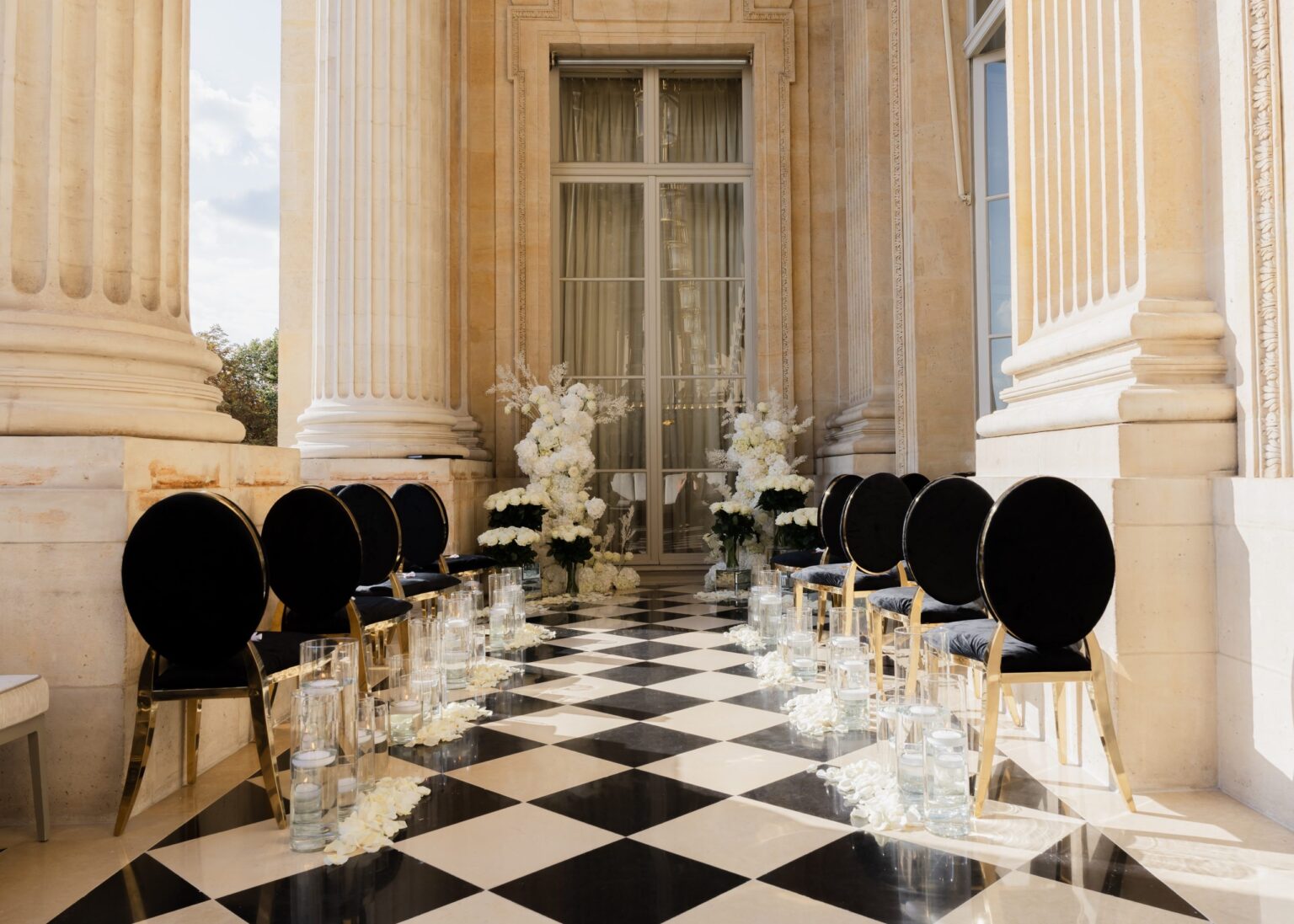 Black chairs lining a checkered-floor colonnade aisle at Hôtel de Crillon