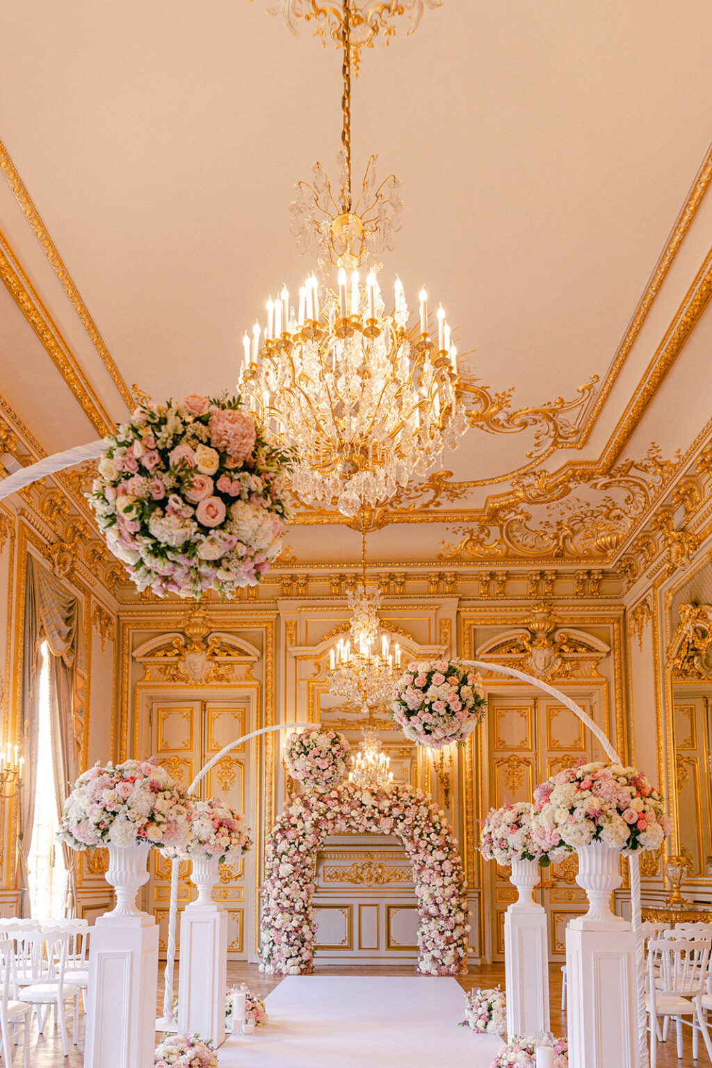 Floral arches along a white aisle beneath crystal chandeliers in a gilded Paris salon, Dream Paris Wedding