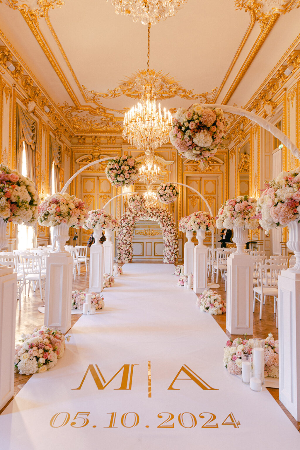 An aisle runner printed with the couple’s monogram and date between white flower columns