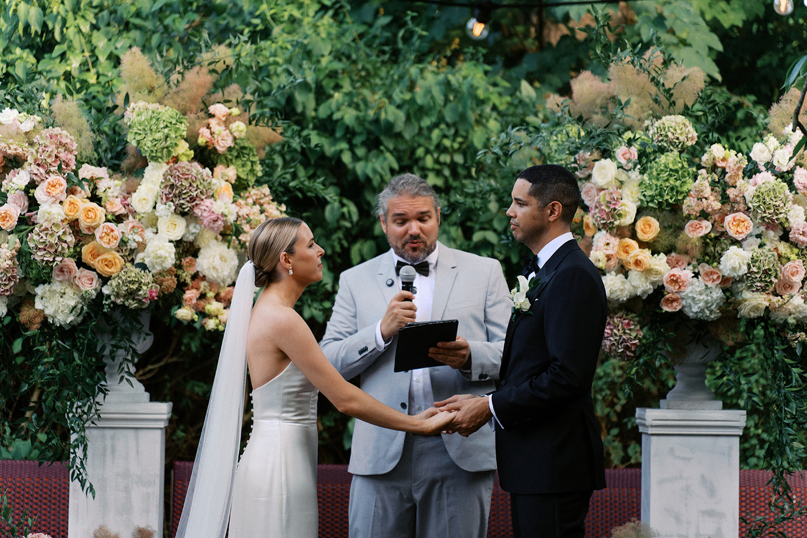 Outdoor vows in front of tall peach and cream flower arrangements, L'ile Restaurant, Dream Paris Wedding