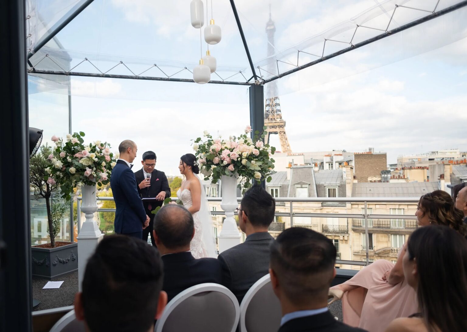 A rooftop ceremony with white chairs and the Eiffel Tower beyond
