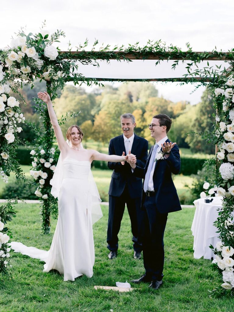 Couple at a white-flower arch on the lawn at Chateau Bouffemont, Dream Paris Wedding