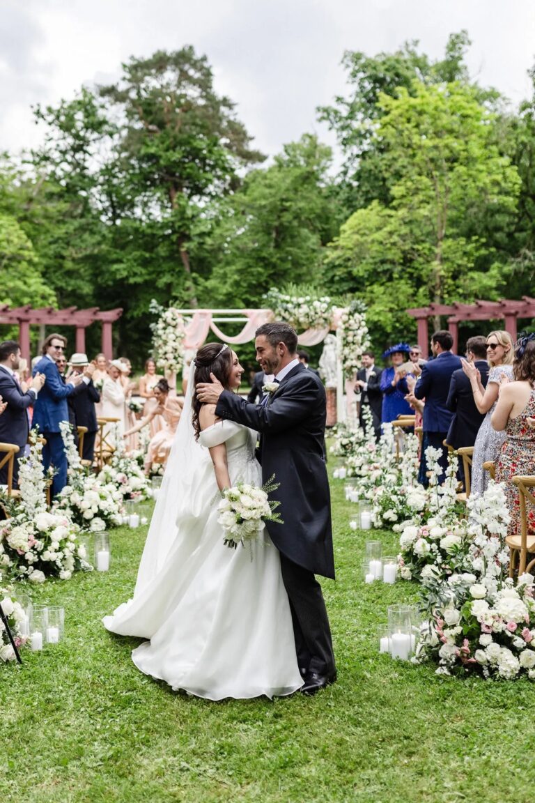 Couple on a lawn aisle edged with white flowers and candles, Dream Paris Wedding