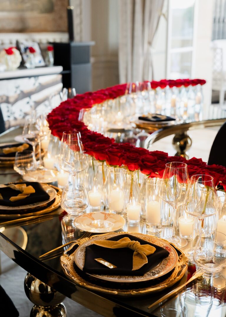 Curved table lined with red roses and candles over black and gold place settings, Dream Paris Wedding