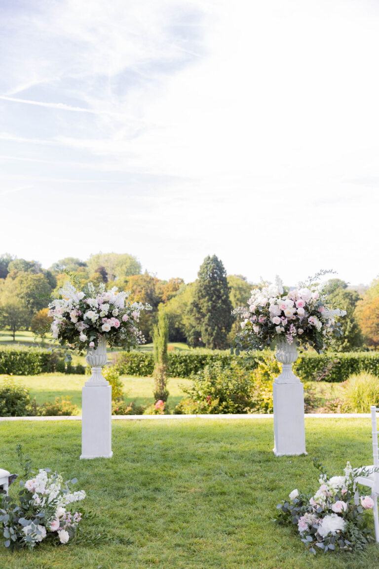 White arch and pedestals of flowers across the lawn at Chateau Bouffemont, Dream Paris Wedding