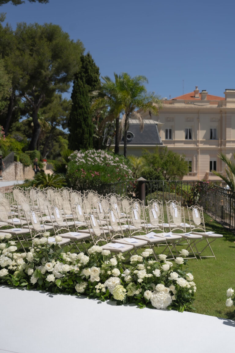 White chairs and low white blooms along the ceremony platform, Dream Weddings Europe