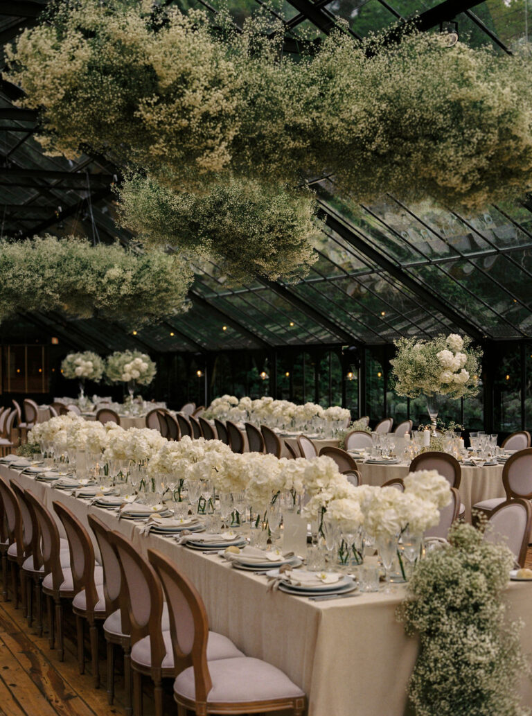 Banquet table under a glass roof with candles, ivory flowers and wooden chairs, Dream Weddings Europe