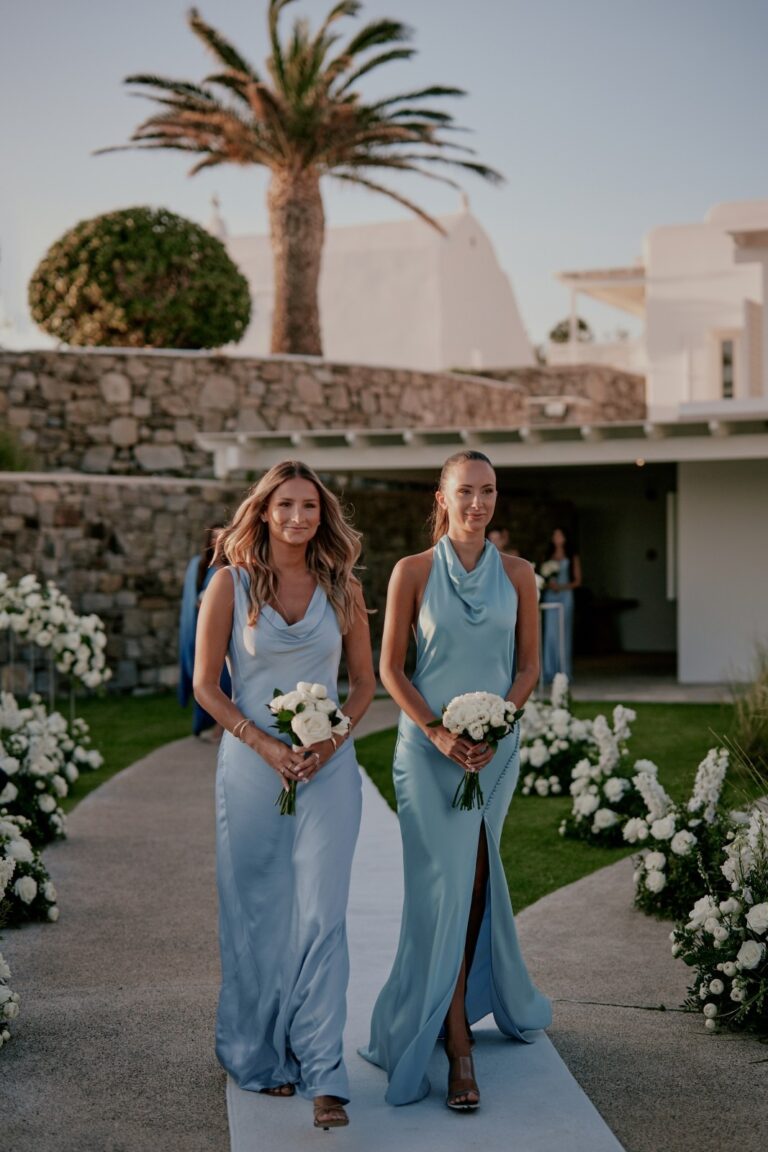 Two bridesmaids in pale blue walking between flower arrangements, Dream Weddings Mykonos