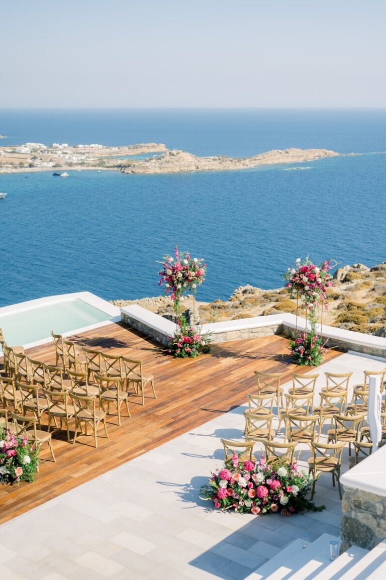 Ceremony chairs on a timber deck with flowers and a view over the sea, Dream Weddings Mykonos