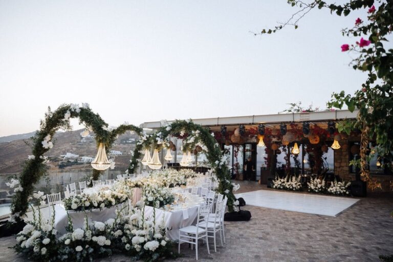 Floral arches over a curved reception table beside the sea at dusk, Dream Weddings Mykonos