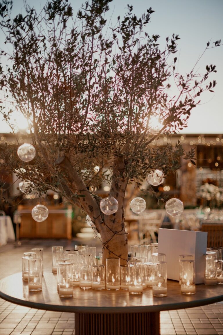 Guest table with an olive-branch centrepiece hung with glass baubles, Dream Weddings Mykonos
