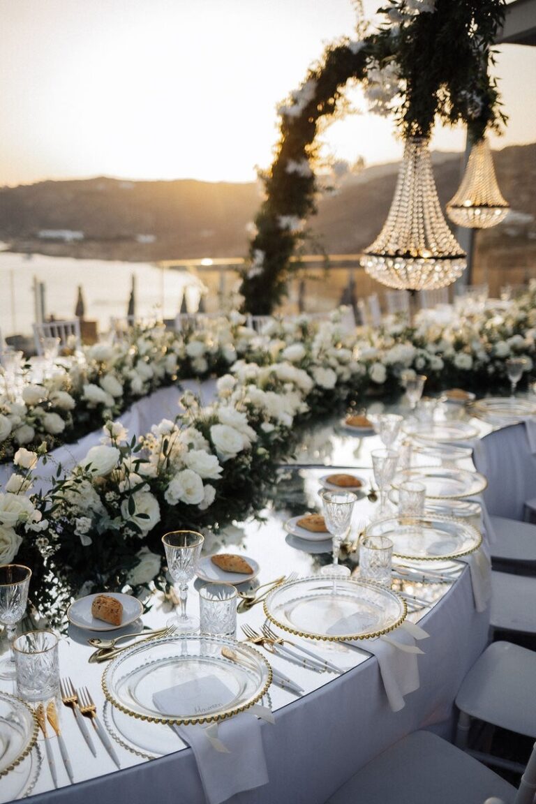 Curved flower-covered reception table under a chandelier at sunset, Dream Weddings Mykonos
