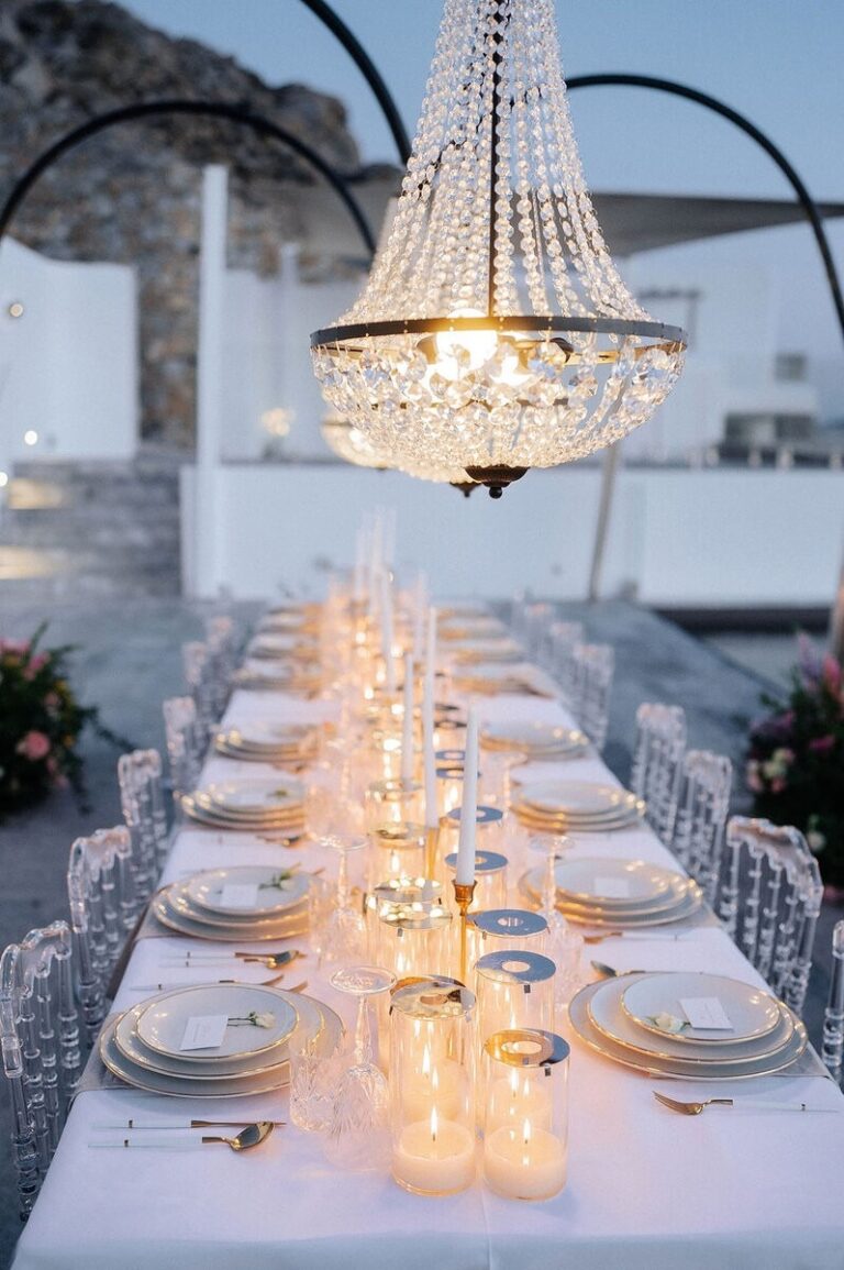 Long dinner table lit by candles under a crystal chandelier, Dream Weddings Mykonos