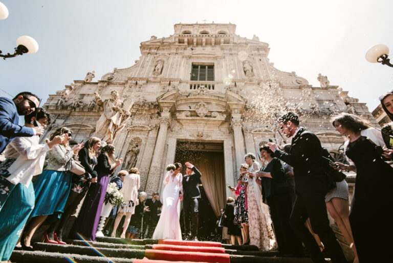 Guests throwing rice as the couple leave a baroque church, DS Studiofotografico