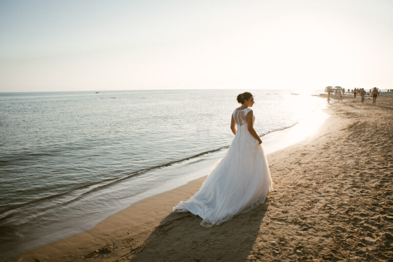 Bride walking along the shoreline in late afternoon light, DS Studiofotografico