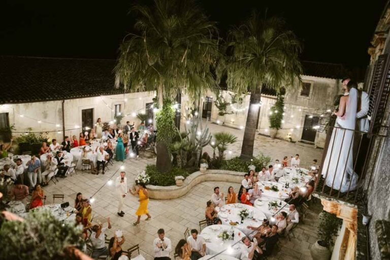 Dinner in a palm-filled courtyard at night, seen from above, DS Studiofotografico