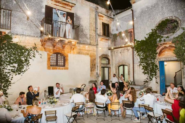Guests at dinner in the courtyard of an old palazzo, the couple on the balcony above, DS Studiofotografico