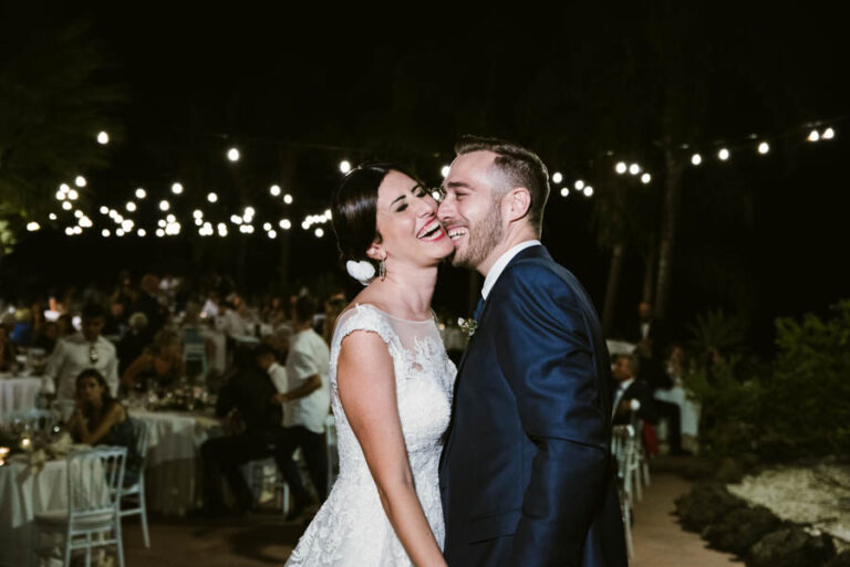 Couple laughing together under string lights at the evening reception, DS Studiofotografico