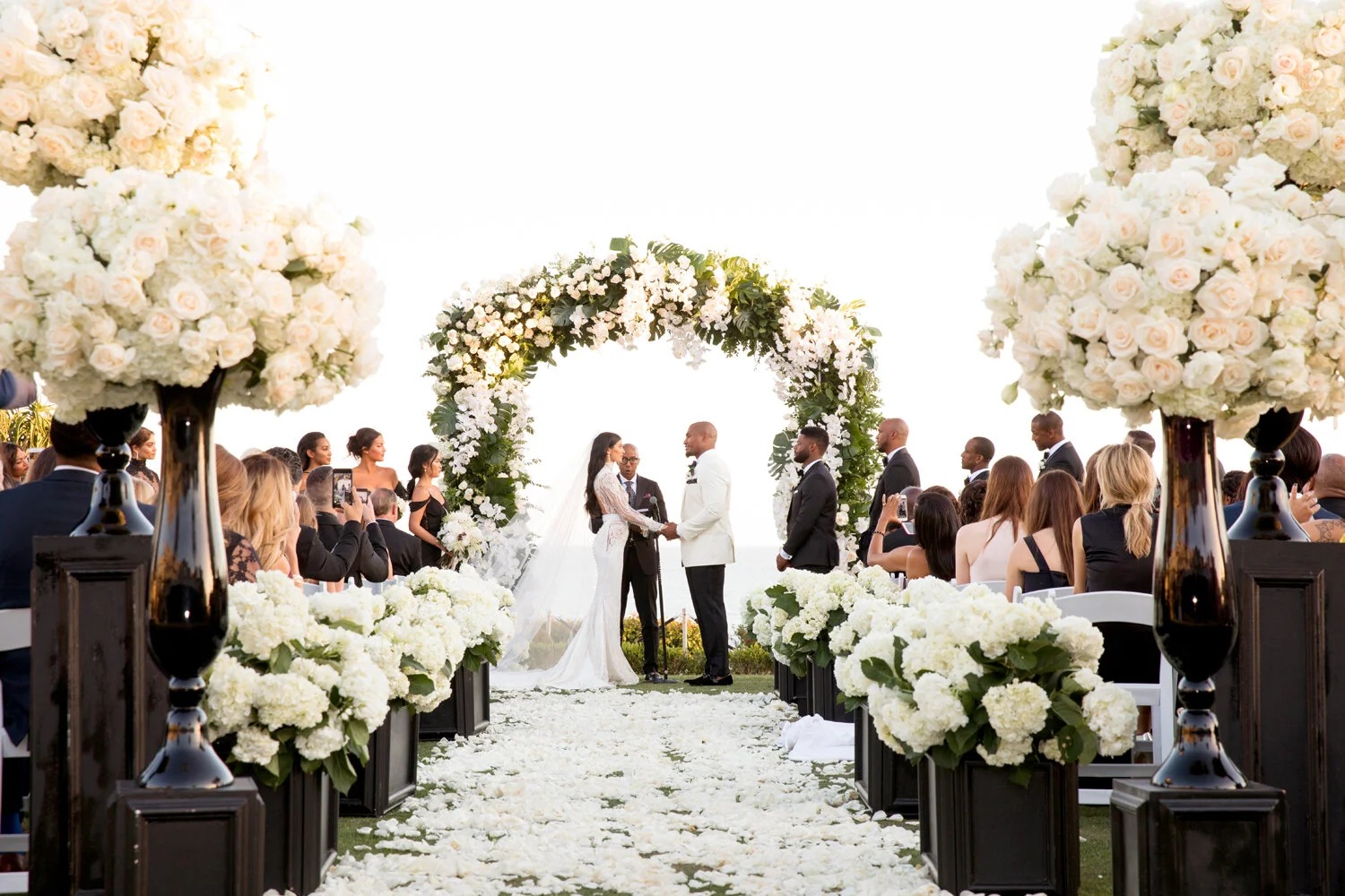 Vows beneath a white floral arch framed by tall arrangements, Montage Laguna Beach, Duke Photography