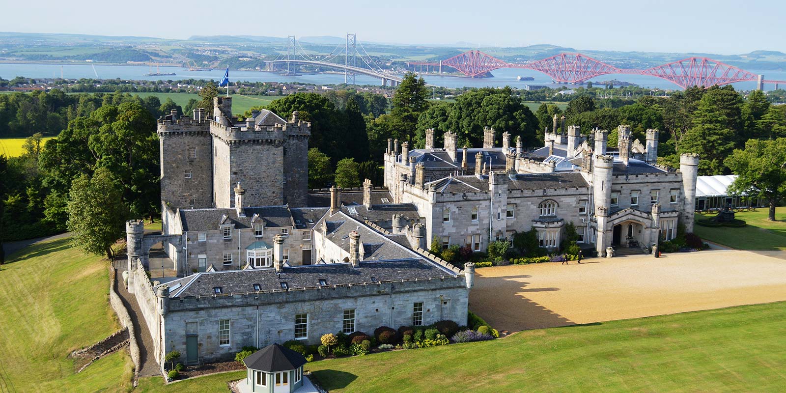 Aerial view of the Auld Keep and the castle with the Queensferry Crossing and the Forth Bridge beyond, Dundas Castle