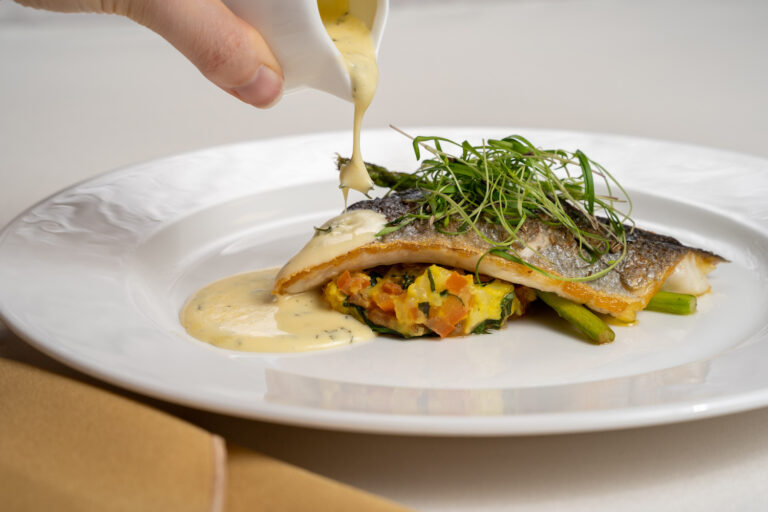 Seared sea bass with asparagus and a butter sauce being poured at the table, Dundas Castle