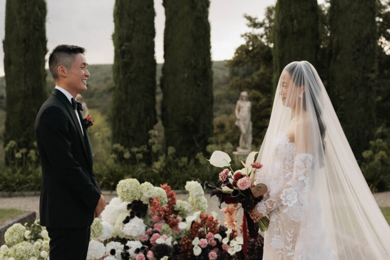 A ceremony among cypresses in a Tuscan garden, deep red and white flowers at the altar, Elisa Prati Wedding Italy