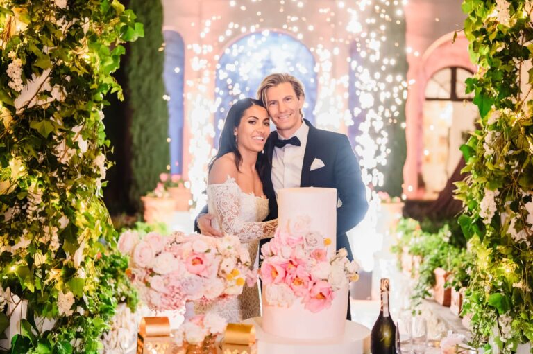 Cutting a pink floral cake in front of sparkler fountains and a wall of greenery, Elisa Prati Wedding Italy