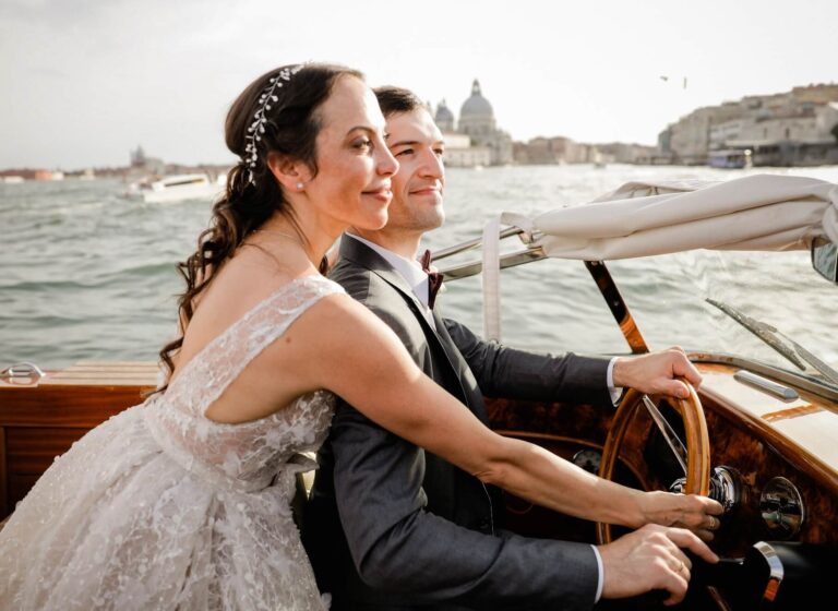 The couple at the wheel of a wooden launch on open water, Elisa Prati Wedding Italy