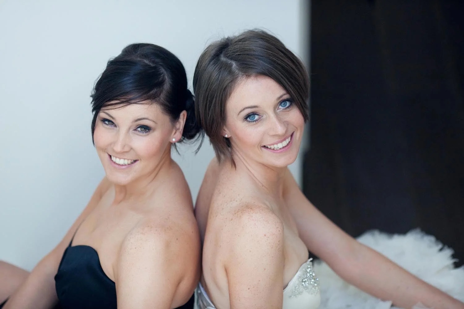 A bride and her chief bridesmaid, matching soft updos, back to back, Elizabeth Hsieh Make Up Artist